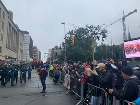 OTTAWA – Sept 19, 2022 – The crowd is four deep at the corner of Wellington and Bay Streets. Here the parade to honour Queen Elizabeth II is turning to make its way to Christ Church Cathedral.