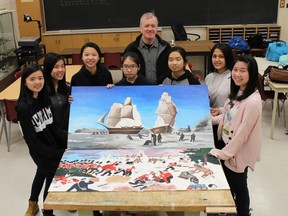 Students and teacher Graham Bye in Albert Campbell Collegiate Institute's mural club pose with murals of the Battle of Queenston Heights and the Franklin expedition.