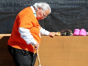 Murray Sinclair pauses solemnly after laying a tiny pair of shoes in place during Friday’s gathering at LeBreton Flats. Sinclair is a former senator and was chairman of the Indian Residential Schools Truth and Reconciliation Commission.