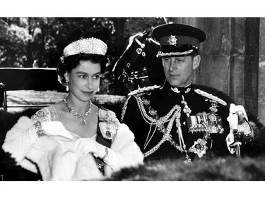 The Queen in her Coronation gown and Prince Philip in the uniform of a Colonel-in-chief of the Royal Canadian Regiment present a royal picture as they drive in an open carriage to open Parliament in Ottawa on October 14, 1957.