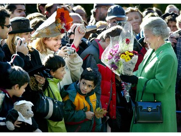 Queen Elizabeth II accepts flowers from the wellwishers during a walkabout following a tree planting ceremony at Rideau Hall in Ottawa, October 13, 2002.