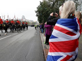 OTTAWA – Sept 19, 2022 – A person wrapped in the Union Jack flag watches the parade from Elgin Street Monday.