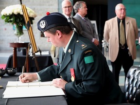 Maj. Robert Baker of the Cameron Highlanders of Ottawa — the official regiment of the city of Ottawa — signs the book of condolences for Queen Elizabeth II at Ottawa City Hall on Friday.