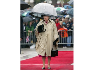 Queen Elizabeth II stands with an umbrella in the rain during a wreath laying ceremony at the war memorial, in Ottawa Sunday Oct. 13, 2002.