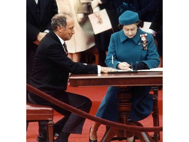 From left to right Prime Minister Pierre Elliott Trudeau, Queen Elizabeth II, Michael Pitfield (with glasses) and Michael Kirby. Constitution signing (1982) document after patriation.