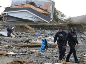 RCMP officers walk around a site destroyed by Hurricane Fiona in Port Aux Basques, Newfoundland on Sept. 26.