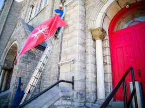 Co-owner Francis Healy removes a TUPOC banner from the front of the Old St. Brigid's Church building in Lowertown on Saturday.