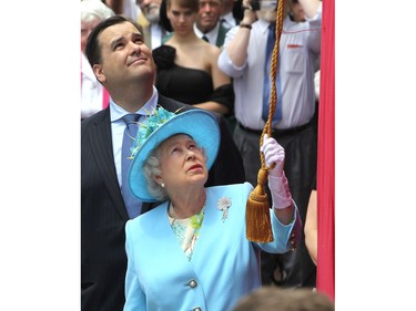 With Heritage Minister James Moore looking on Queen Elizabeth prepares to unveil a statue of Canadian pianist Oscar Peterson June 30, 2010, outside the National Arts Centre during a stop on the Royal Tour.