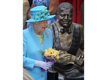 Queen Elizabeth walks past a statue of Canadian jazz pianist Oscar Peterson in Ottawa, Ontario, June 30, 2010, after she officially unveiled the larger than life artwork installed outside the National Arts Centre as she continues on the Royal Tour of Canada.