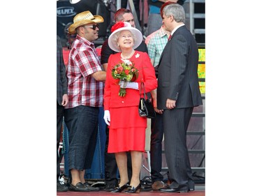 Prime Minister Stephen Harper (r) greets members of the Bare Naked Ladies while Queen Elizabeth turns to watch the Snowbirds fly over at the end of the noon hour festivities on Parliament Hill for Canada Day, July 1, 2010.