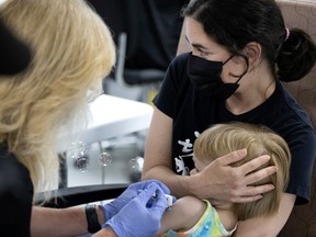 A woman holds her child as he is given a COVID-19 vaccination Montreal