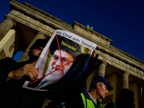 A demonstrator displays a portrait of Iran's supreme leader Ali Khamenei inscribed with the word terrorist during a rally in support of protesters in Iran, in Berlin on October 7, 2022. - A wave of unrest has rocked Iran since September 16 over the death of Mahsa Amini, 22, after morality police arrested her in Tehran for allegedly failing to observe the Islamic republic's strict dress code for women.