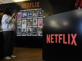 A visitor takes pictures beside 2022 Netflix Korea series and film posters during the 27th Busan International Film Festival in Busan, South Korea, Friday, Oct. 7, 2022.