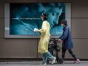 Ein Mitarbeiter des Gesundheitswesens führt eine Frau, die während der COVID-19-Pandemie eine Maske trägt, vor dem St. Michaels Hospital in Toronto.