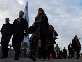 Pedestrians on their way to work, cross London Bridge, with the Shard behind, in central London on October 12, 2022. - Britain's economy unexpectedly shrank in August after slender growth the previous month, hit by the cost-of-living crisis and rocketing energy bills, official data shows.
