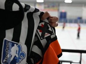 A referee wears a Hockey Canada patch crossed with a black ribbon during an ice hockey game, to generate discussion and raise awareness as the hockey federation faces a sexual assault scandal.