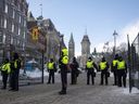 The Peace Tower is seen behind police at a gate along Queen Street as they restrict access to the streets around Parliament Hill in Ottawa, Saturday, Feb. 19, 2022. The inquiry into the federal government's use of the Emergencies Act during February's 