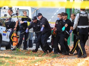 A victim is carried to an ambulance in the 3900-block of Canada Way in Burnaby on Tuesday, Oct. 18, 2022. An RCMP officer was killed and police shot and injured a suspect.