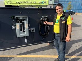 Raymond Leury, president of the Electric Vehicle Council of Ottawa, shows a display model of an electric vehicle charging station during a test drive event.