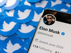 Elon Musk's Twitter profile is seen on a smartphone placed on printed Twitter logos in this photo illustration.