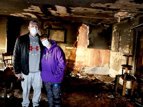 Mike and Kirsti Bakker pose in the charred remains of their Bisseltown Road living room on Tuesday afternoon.