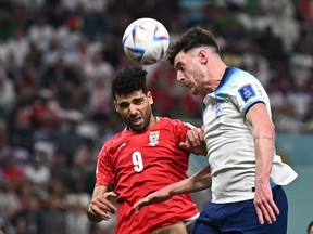 England's midfielder Declan Rice (right) heads the ball past Iran's forward #9 Mehdi Taremi during the Qatar 2022 World Cup Group B football match between England and Iran at the Khalifa International Stadium in Doha, Nov. 21.