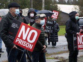 North Grenville residents carry signs as they protest the site of a proposed correctional facility in 2021 
