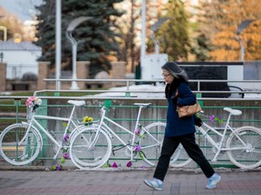 Files: A woman walks past ghost bikes on display outside of Ottawa City Hall.