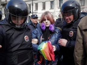 In this Monday, May 1, 2017 file photo, a gay rights activist holding a rainbow umbrella is detained by police during a rally marking May Day in downtown St. Petersburg, Russia.