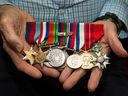 Robert Spencer, then 95, holding his World War II service medals.