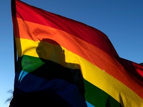 A commuity members silhouette is seen through a Pride flag while paying their respects to the victims of the mass shooting at Club Q, an LGBTQ nightclub, in Colorado Springs, Colorado, on November 20, 2022.