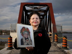 The new chancellor of the University of Ottawa, Claudette Commanda, holds a picture of her grandfather, Chief William Commanda, at the foot of the old Prince of Wales Bridge renamed in his honour Thursday.