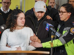 Paramedic Jayme Erickson, left, who was called to a crash last week and didn't know she was trying to save her own daughter because the injuries were too severe, is comforted by her husband Sean Erickson, centre, and friends as she speaks to the media in Airdrie, Alta., Tuesday, Nov. 22, 2022.THE CANADIAN PRESS/Jeff McIntosh