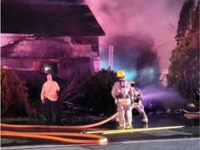 An Ontario Provincial Police photo shows firefighters battling a blaze after a vehicle crashed into a house near Highway 15 at Portland, Ont.