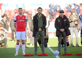 Wrexham owners Ryan Reynolds and Rob McElhenney stand with wreaths as part of remembrance commemorations ahead of a National League match in 2021. Action Images via Reuters/Paul Burrows