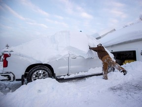 Clint Coggins cleans the snow from his vehicle during a break in the snow storm hitting the Buffalo area, in Orchard Park, New York, U.S. November 19, 2022