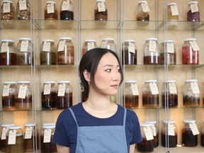 Briana Kim du restaurant Alice, devant une armoire d'ingrédients en fermentation.