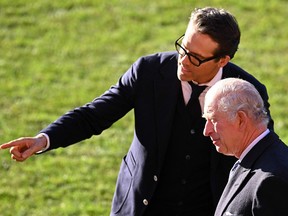 Wrexham AFC Co-Chairman, US actor Ryan Reynolds gestures towards the team's players as he talks with Britain's King Charles III during his visit to Wrexham Association Football Club in north Wales on December 9, 2022.