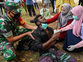 Health workers check a Rohingya refugee who was feeling sick after his arrival by boat in Krueng Raya, Indonesia's Aceh province on Dec. 25, 2022.