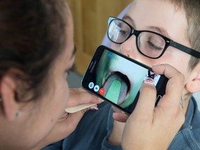 A doctor examines the throat of a child via a smartphone held by a nurse during a digital medical consultation. Ever-advancing phone apps may soon make it even easier to see a doctor remotely, writes Josh Freed.