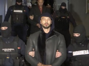In this grab taken from video released by Observator Antena 1, Andrew Tate is led away by police, in the Ilfov area, north of Bucharest, Romania, Thursday, Dec. 29, 2022. Romanian news outlets are reporting that the divisive social media personality has been arrested on charges of human trafficking and rape.