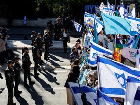 People hold signs and flags as they protest outside the Knesset, Israel's parliament, on the day the new right-wing government is sworn in, with Benjamin Netanyahu as Prime Minister, in Jerusalem December 29, 2022.