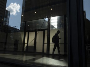 A man walks though a downtown Toronto office building with other buildings reflected in a window in this June 11, 2019 photo. A new survey suggests many Canadians don't plan on using all their vacation before the end of the year.THE CANADIAN PRESS/Graeme Roy