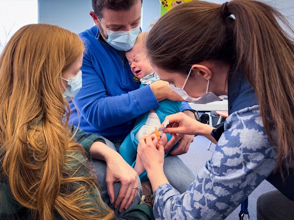 A child is comforted by his parents as he receives a COVID-19 vaccine from Ottawa Public Health. FILE PHOTO