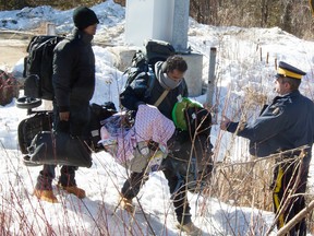 The RCMP helps a group of asylum seekers at the border at Roxham Road in Quebec, in this file photo.