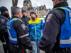 Mathieu Venne of Val-des-Monts, Que., speaks with Ottawa Police Service liaison officers at Parliament Hill on Saturday.
