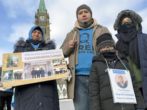 A Uyghur family from East Turkistan displays photos of jailed or missing family members, on Parliament Hill in November 2021.