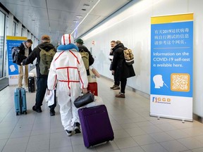 Travelers arriving from China walk past information banners and receive free Covid-19 self-test kits, at Amsterdam's Schiphol Airport on Jan. 4, 2023.  More than a dozen countries have imposed coronavirus testing requirements on visitors from China, which is experiencing an explosion of cases after lifting its long-standing zero-COVID measures.