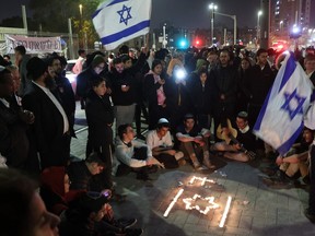 Israeli youths hold a candlelight vigil at the site of last night's shooting attack, in annexed east Jerusalem on Jan. 28, 2023. - Israeli Prime Minister Benjamin Netanyahu vowed to take forceful and timely measures following two attacks in annexed east Jerusalem carried out by Palestinians, one of which killed seven Israelis. The attacks came after one of the deadliest army raids in the occupied West Bank in two decades, rocket fire from militants in the Gaza Strip and retaliatory Israeli air strikes.