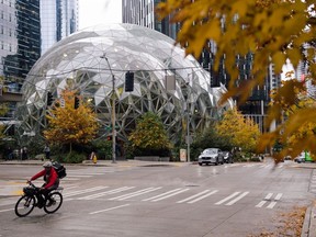 A delivery worker travels past the Amazon Spheres, part of the Amazon headquarters campus, in the South Lake Union neighbourhood of Seattle, Washington.